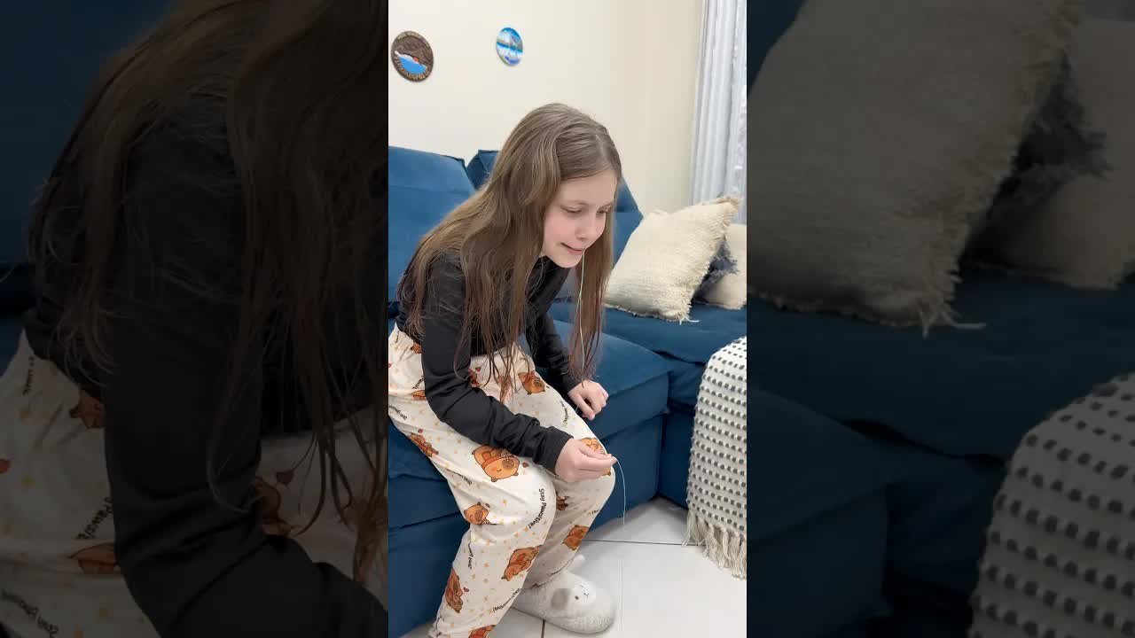 A menina puxa o dente com fio dental